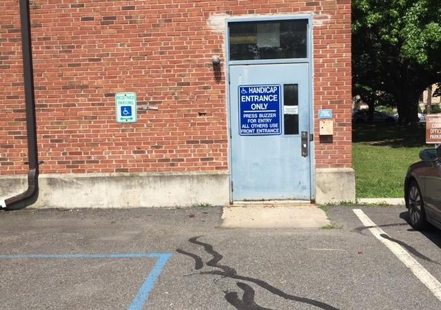 Entrance from the parking area. It is a single door with  ADA signage. It is accessed from street level.