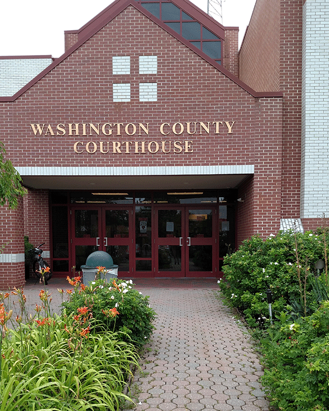A walkway leading to the Washington County Courthouse. The entrance to the courthouse has two double doors.
