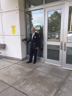 The photo is of a man pushing the button to access the doors. He is standing in front of a set of doors.