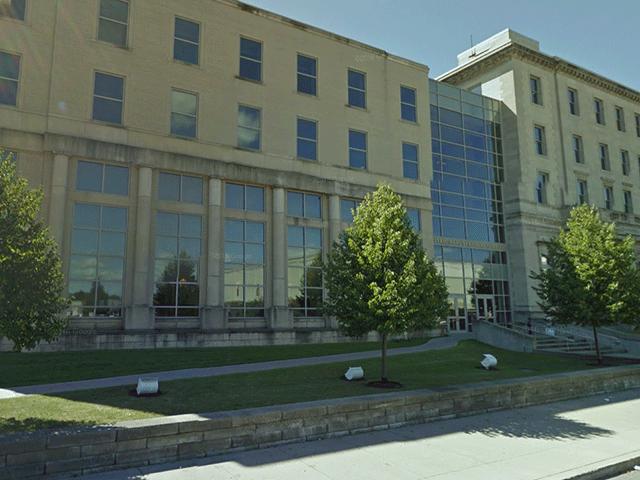 An angled view of the courthouse. There is a walkway between two grassy areas that leads to the entrance. There are stairs that lead driectly to the entrance from the sidewalk.
