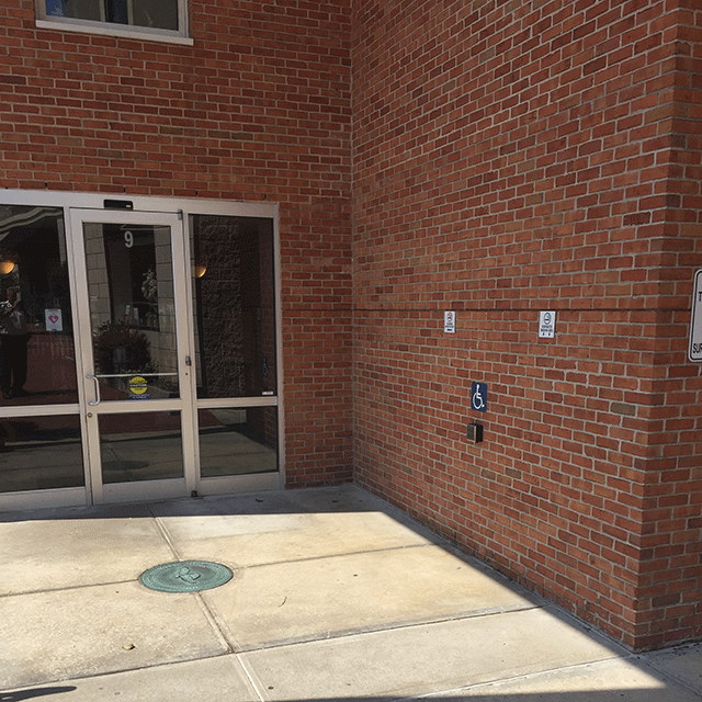 The courthouse has a single door. To the right on the side of the buidling is a push button to open the door.