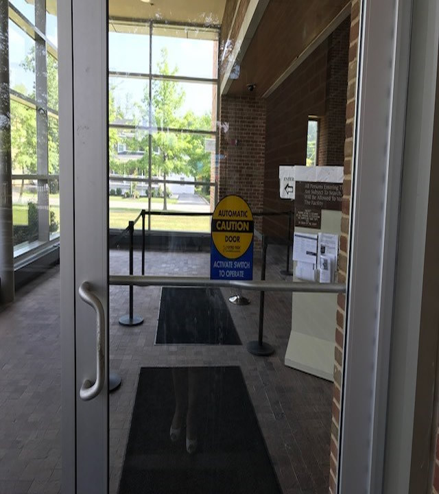 A door that is accessed on street level. The door has a sign that is an automatic door and can be activated with a switch.