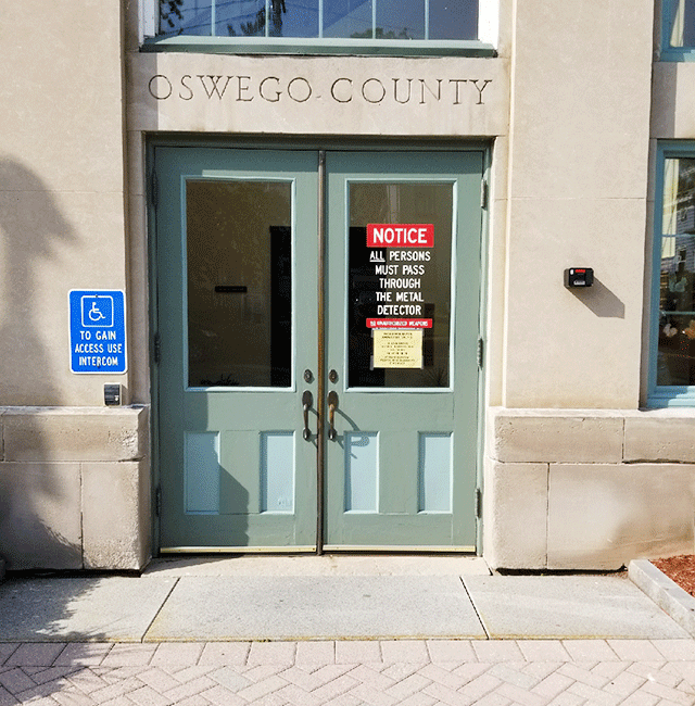 A double door ADA-accessible entrance with signage. The doors are accessed from the street level.