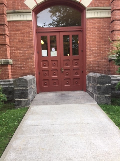 A walkway that leads to  an entrance of double doors.