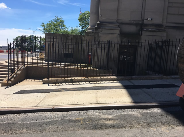 An entrance to a ramp from the sidewalk. The ramps lead to a double door entrance to the court facility.