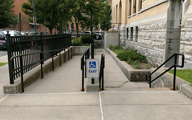 A walkway that leads to a ramp on the left and down the steps to the right. The entrance to the court facility is on the far right.