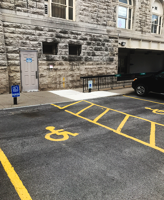Entrance from the parking lot area. There are two ADA-accessible parking spaces directly in front of the entrance. The entrance is on street level.