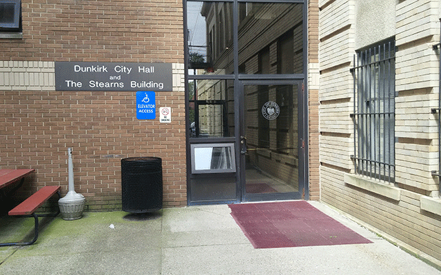 The photo is of a single door. To the left attached to the building is signage for elevator access.