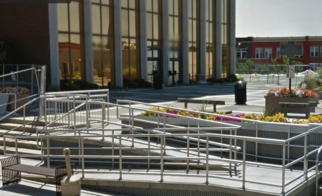 A winding ramp and stairs that lead to an open area. The entrance to the facility is located on the far right.