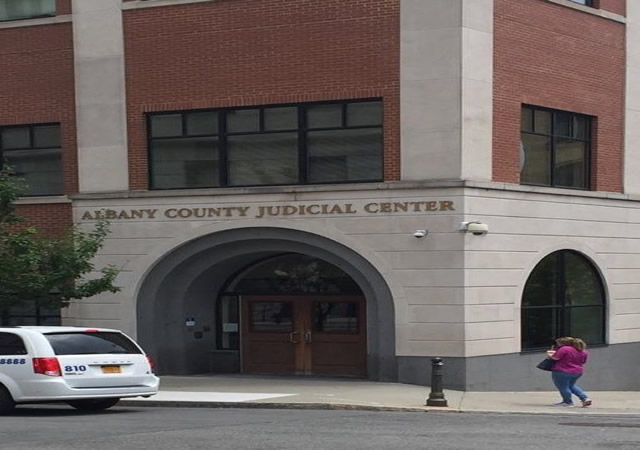 Albany County Judicial Center's main entrance. The entrance contains two doors at street level and a push button to the left of the entry.