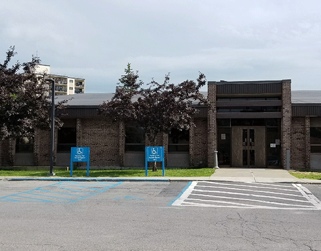 A view of Gloversville County Courthouse from the parking area. There are two ADA-accessible parking spaces to the left of the walkway that leads to the street level entrance.