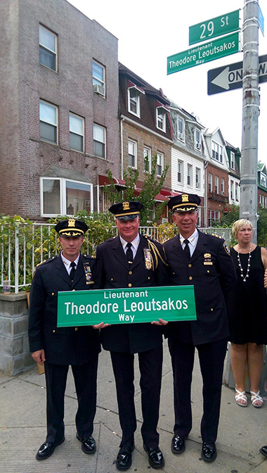 Court officers holding sign for Lieutenant Theodore Leoutsakos Way on street corner