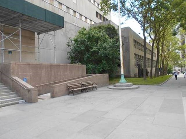 A view of the courthouse from the sidewalk. There are steps to the left and directly to the right is the entrance the ramp. The courthouse extends to the end of the block.